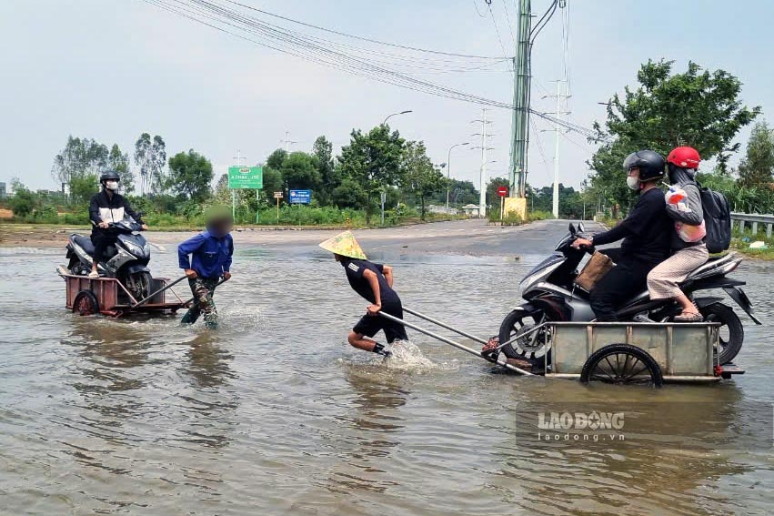 Dịch vụ kéo xe qua điểm ngập trên đường gom Đại lộ Thăng Long. Ảnh: Tô Thế