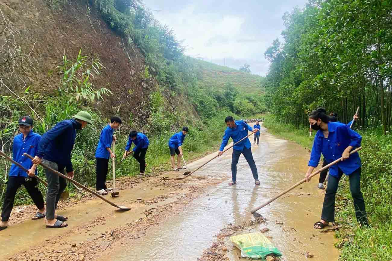 Thanh niên dọn đất đá sạt lở trôi ra đường. Ảnh: Đoàn Tuấn. 