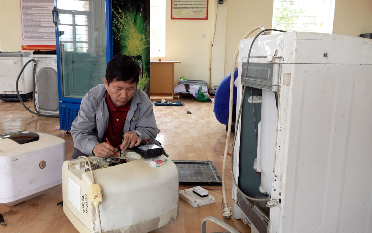 Thầy giáo trong nhóm tình nguyện đang sửa chữa bình nóng lạnh cho người dân vùng lũ tại Quảng Ninh. Ảnh: Đoàn Hưng