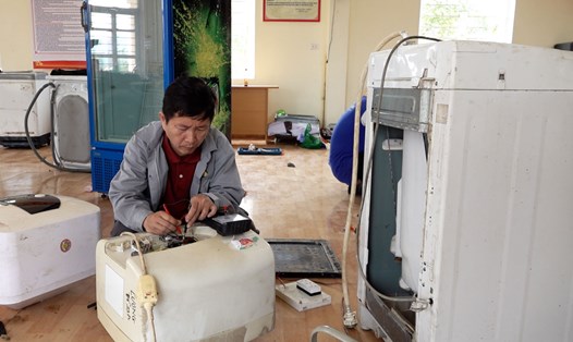 Thầy giáo trong nhóm tình nguyện đang sửa chữa bình nóng lạnh cho người dân vùng lũ tại Quảng Ninh. Ảnh: Đoàn Hưng