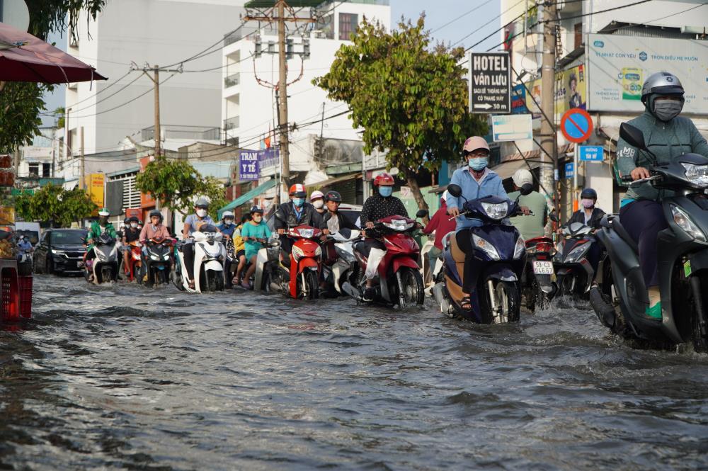 Đường Trần Xuân Soạn ngập nước do triều cường dâng cao, việc đi lại của người dân gặp nhiều khó khăn. Ảnh: Nguyên Chân