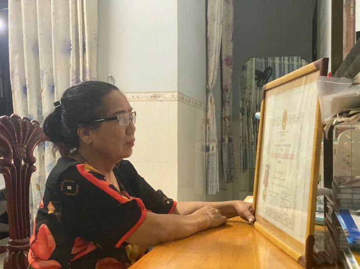 Bà Nguyễn Thị Cúc bên Huân chương Kháng chiến hạng Ba của mẹ. Ảnh: Hưng Thơ