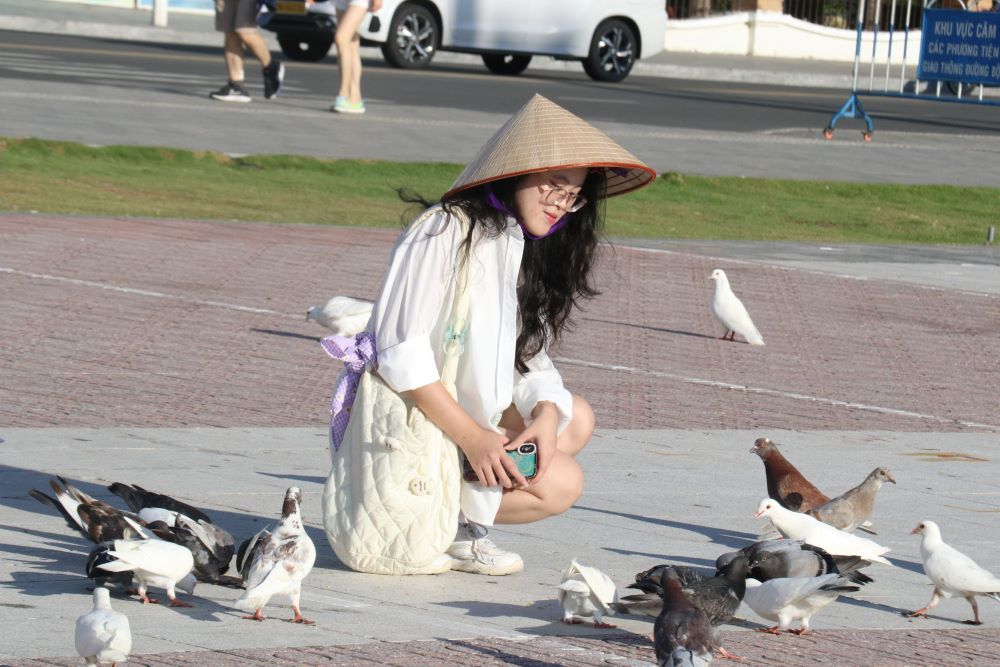 International visitors play with pigeons at April 2 Square, Nha Trang. Photo: Phuong Linh
