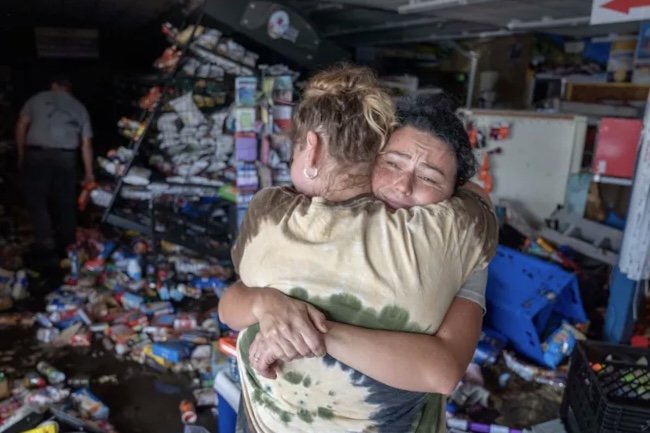 Cassandra Randall, ben phai, duoc Jessica Downey om ben trong mot cua hang tap hoa Maddie's bi hu hai o Steinhatchee, Florida, vao ngay 27.9. Anh: USA Today