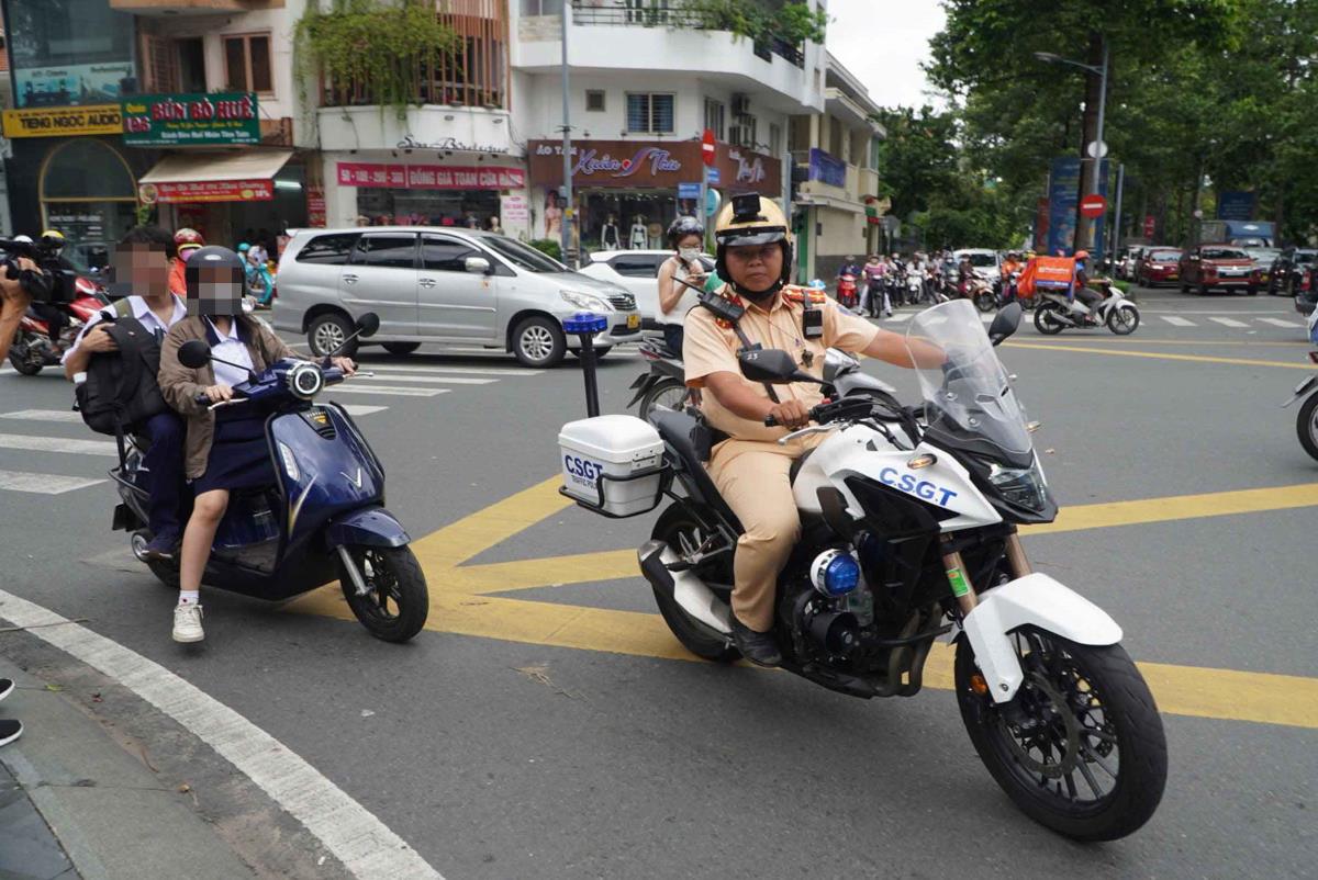 BT female student driving electric motorbike carrying a passenger without wearing helmet. Photo: Chan Phuc