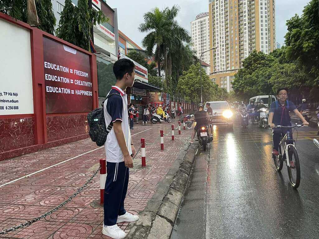 Pham Hai Lam (Da Tri Tue Primary, Secondary and High School) stands at the school gate waiting for his parents to pick him up. "Normally we would leave around 4:15 p.m., but today the school announced that we would be off 2 periods early to avoid the storm. Tomorrow, according to the schedule, I will also be off school." Photo: Thuy Linh