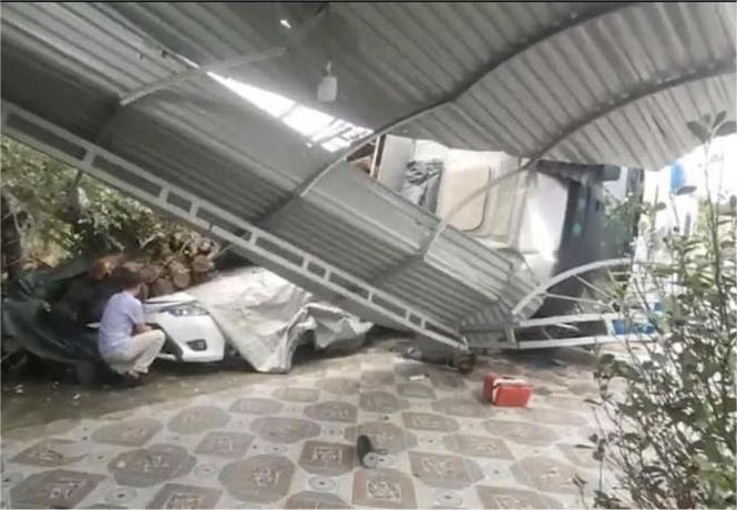 Car and house roof damaged by wood from overturned truck. Photo: Vinh Huong.