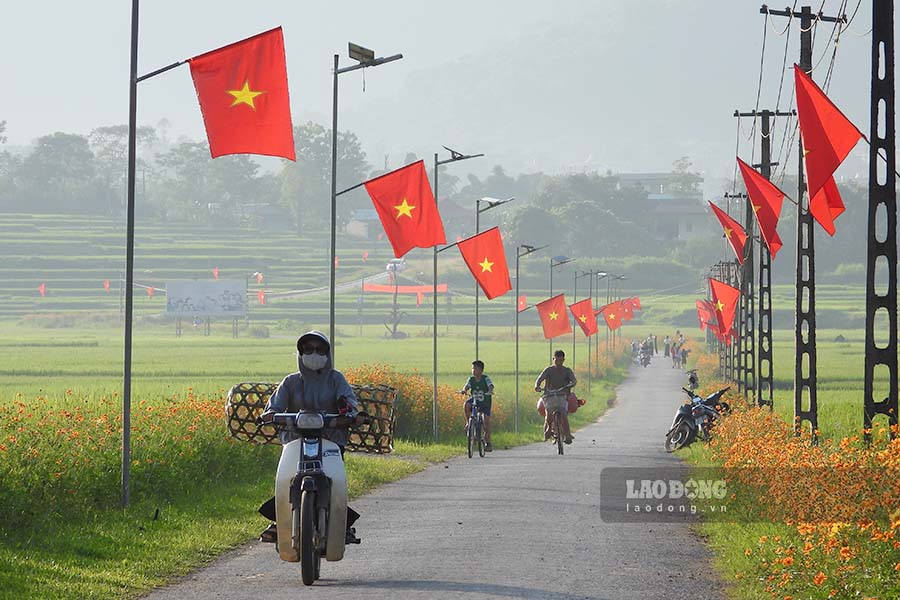 Cờ đỏ sao vàng tung bay trong gió tại con đường hoa vào xã Ẳng Cang.