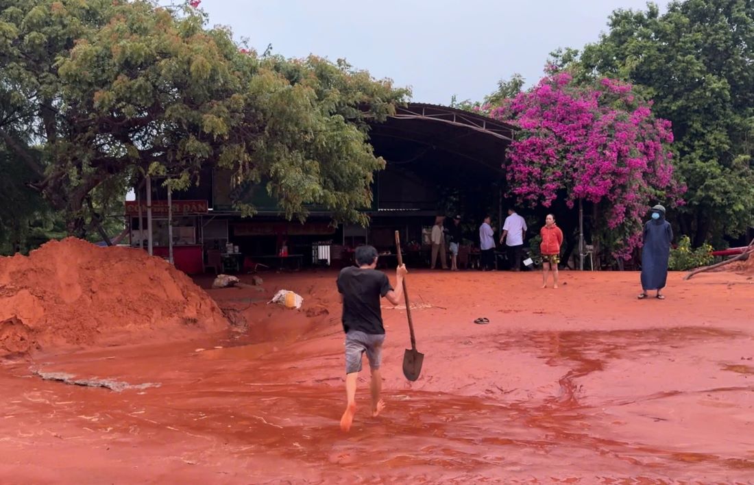 Anh Đức (áo thun đen) chạy đi mượn cái xẻng để đào cát, lấy xe máy bị cát lấp ra. Ảnh: Duy Tuấn