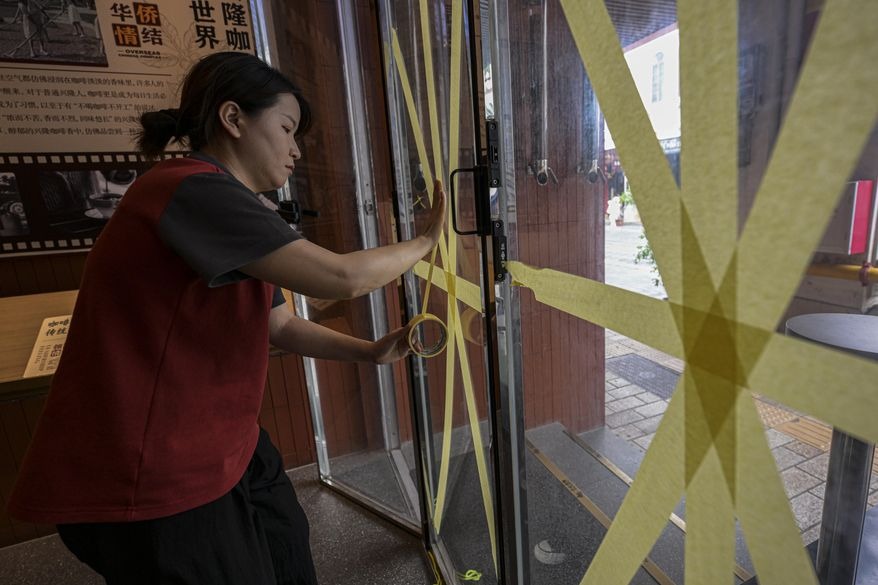 Chinese people tape the glass doors of a cafe in Hekou, Hainan, China, on September 5, before Typhoon Yagi made landfall in the locality. Photo: Xinhua