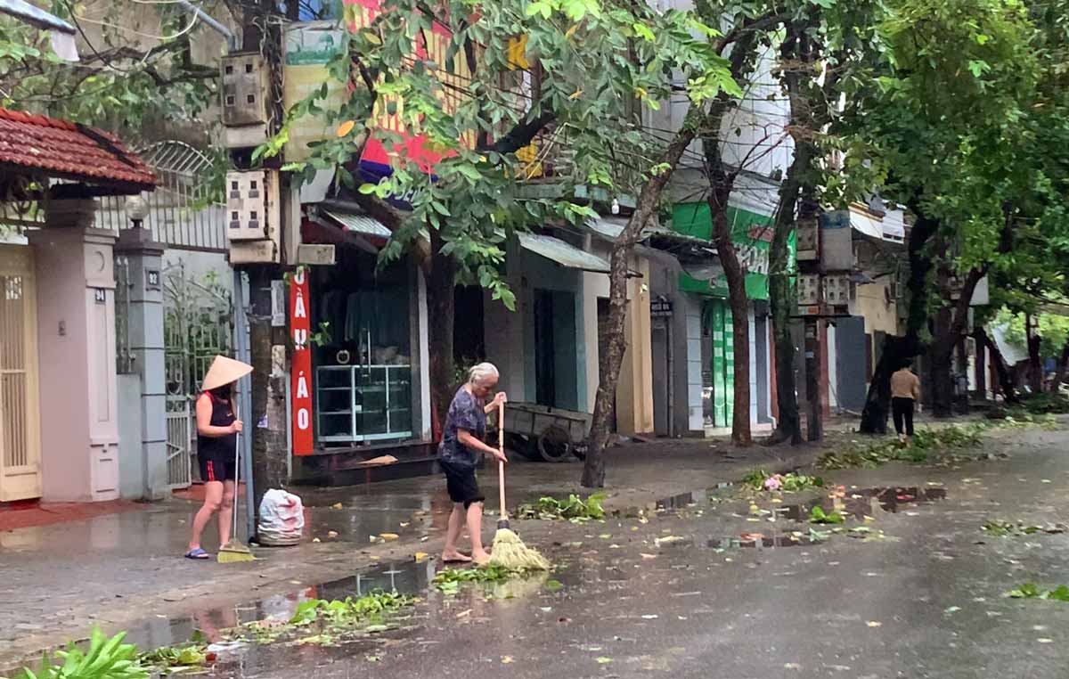 Người dân khu vực TP Nam Định tranh thủ dọn dẹp cành lá cây trước cửa nhà khi trời ngớt mưa. Ảnh: Lương Hà