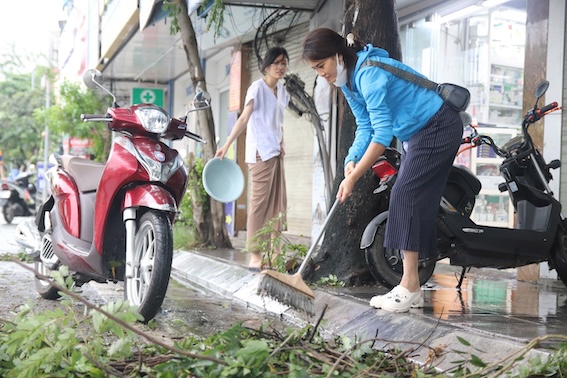 Chị Minh Hạnh (Hai Bà Trưng, Hà Nội) tới dọn dẹp khu vực trước cửa hàng kinh doanh nhà mình. Chị Hạnh cho biết cửa hàng không bị ảnh hưởng nhiều sau bão số 3, trước cửa chủ yếu tồn đọng cành cây gãy đổ. Ảnh: Hoàng Xuyến. 