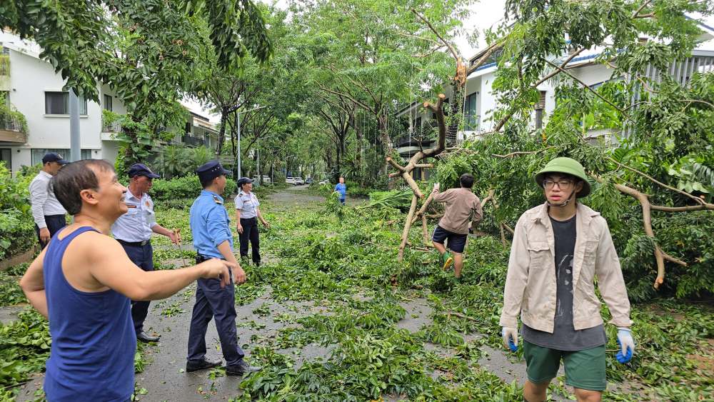 Xuan Bac's son wears a pith helmet and gloves to clean up the street after the storm. Photo: Facebook character