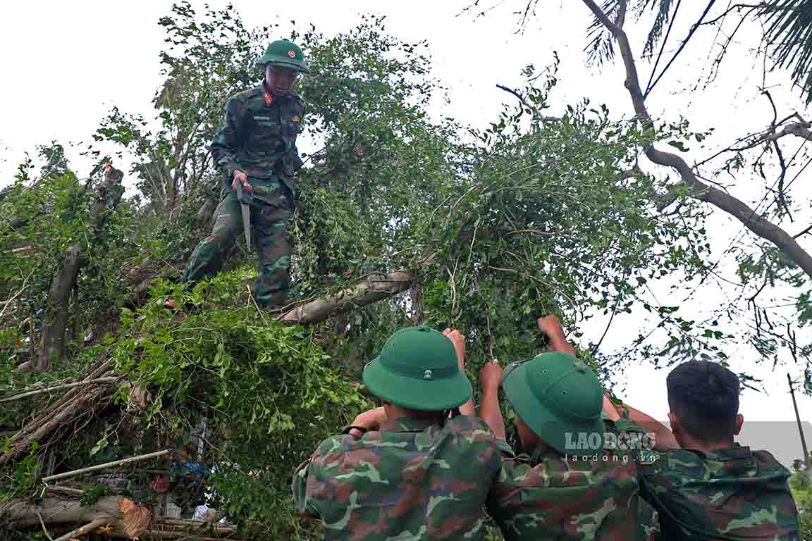 Các chiến sĩ bộ đội phát quang cây cối bị gãy đổ trên đường.