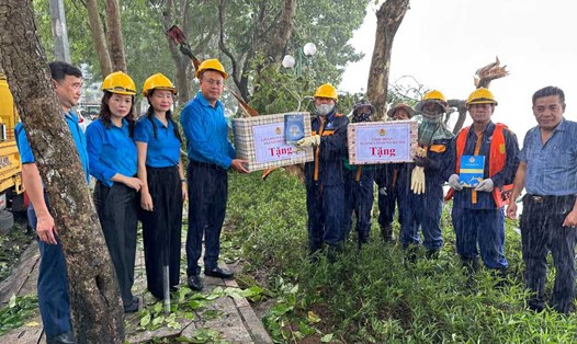 Ông Phạm Quang Thanh, Ủy viên Đoàn Chủ tịch Tổng LĐLĐVN, Chủ tịch LĐLĐ TP Hà Nội và bà Nguyễn Thị Thanh, Chủ tịch Công đoàn ngành Xây dựng Hà Nội tặng quà công nhân Công ty TNHH MTV Thoát nước Hà Nội đang dọn cây đổ bên bờ Hồ Tây. Ảnh: Việt Lâm
