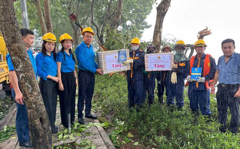 Ông Phạm Quang Thanh, Ủy viên Đoàn Chủ tịch Tổng LĐLĐVN, Chủ tịch LĐLĐ TP Hà Nội và bà Nguyễn Thị Thanh, Chủ tịch Công đoàn ngành Xây dựng Hà Nội tặng quà công nhân Công ty TNHH MTV Thoát nước Hà Nội đang dọn cây đổ bên bờ Hồ Tây. Ảnh: Việt Lâm