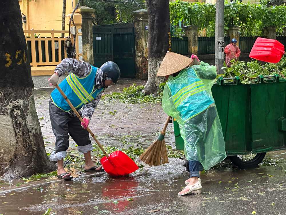 Environmental sanitation workers in Hanoi strain to clear branches and leaves. Photo: Viet Lam