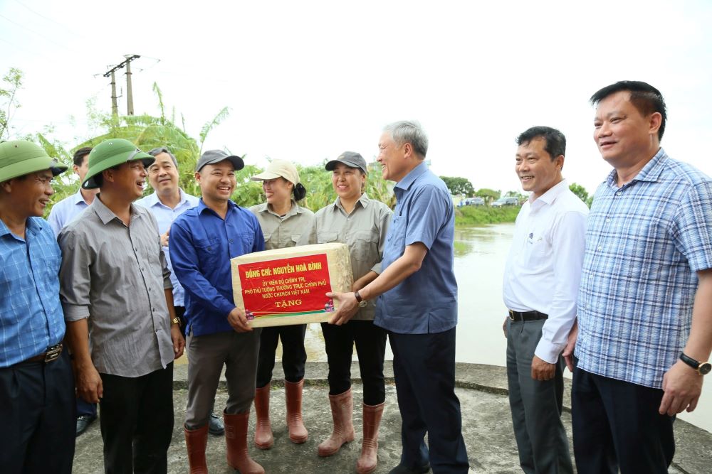 Phó Thủ tướng Thường trực Chính phủ Nguyễn Hòa Bình tặng quà cho cán bộ thủy nông làm nhiệm vụ ứng trực tiêu thoát nước tại trạm bơm An Quốc (xã Quốc Tuấn, huyện Kiến Xương). Ảnh: Nam Hồng