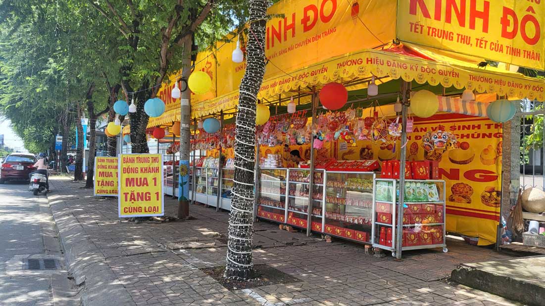 Many mooncake stalls hang up buy-one-get-one-free promotion signs to attract customers. Photo: My Ly