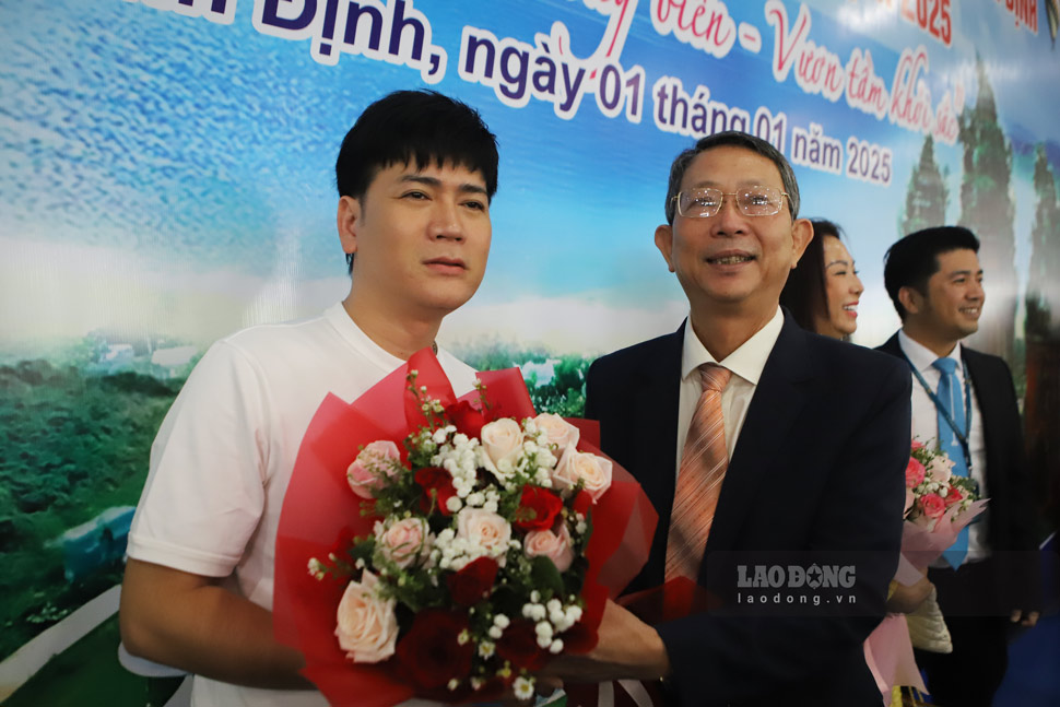 Director of Binh Dinh Department of Tourism Tran Van Thanh presents flowers to singer Quach Thanh Danh. Photo: Hoai Luan