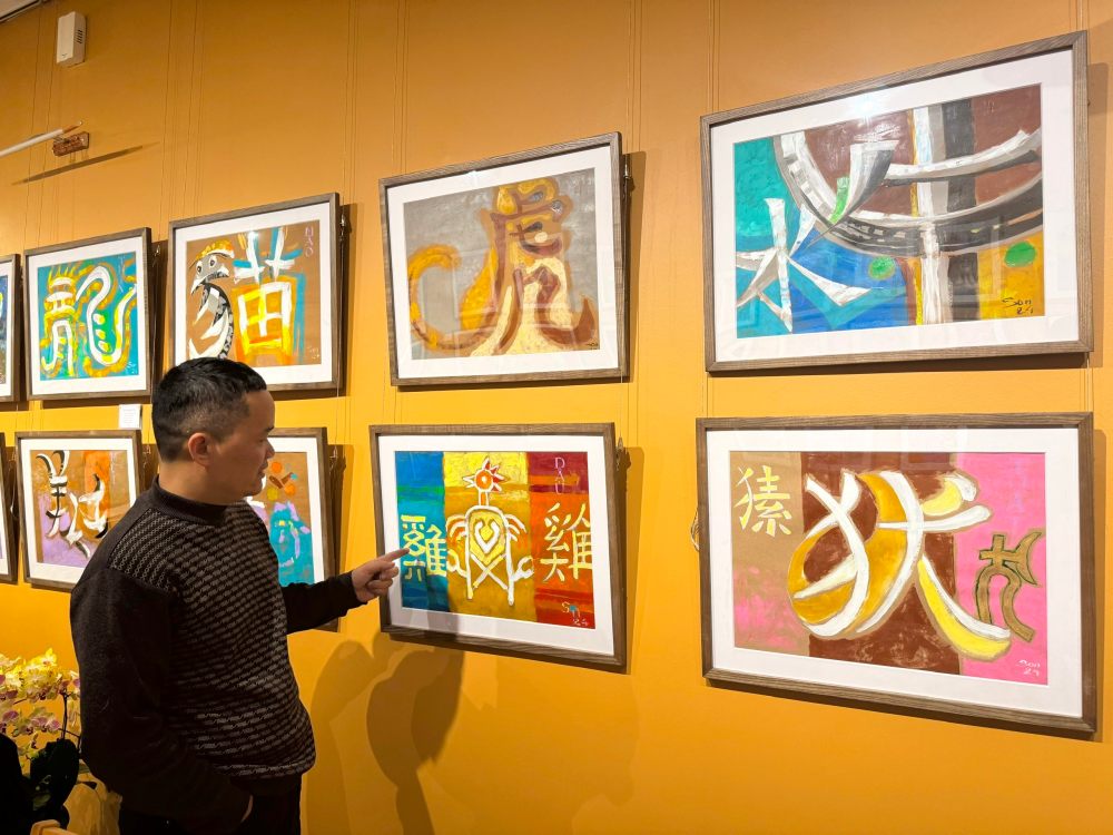 Painter Nguyen Doan Son next to his works at the exhibition. Photo: Interviewee