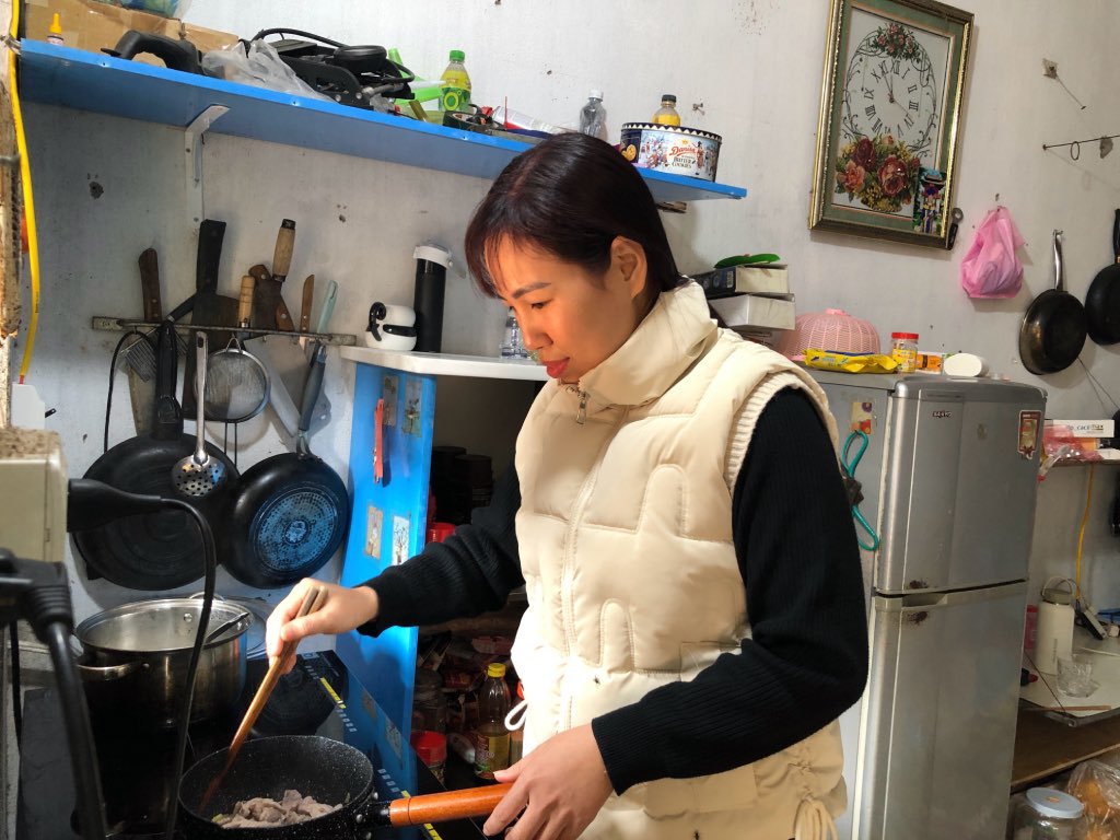 Female worker Nguyen Thi Thanh Huyen cooks in one of the three rented rooms. Photo: Bao Han