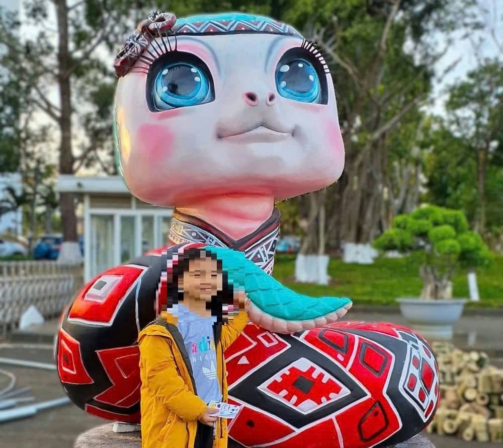 A child takes a photo next to a snake with traditional brocade colors. Photo: Thanh Tuan