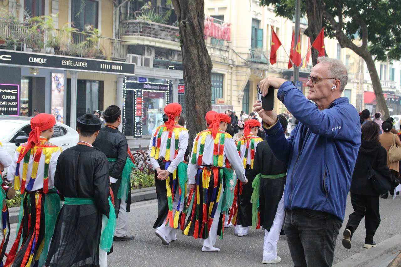 Dong dao nguoi dan va du khach quoc te hao hung xem doan ruoc ruc ro sac ao va hoa di tren pho.