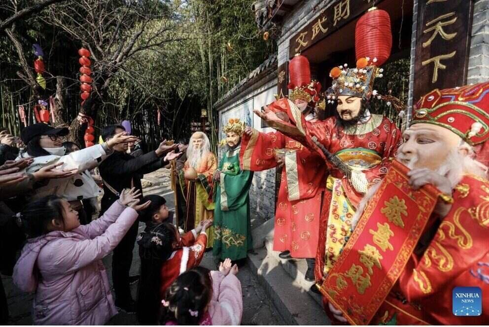 Actors dressed as God of Wealth interact with tourists in Shandong Province, China. Photo: Xinhua