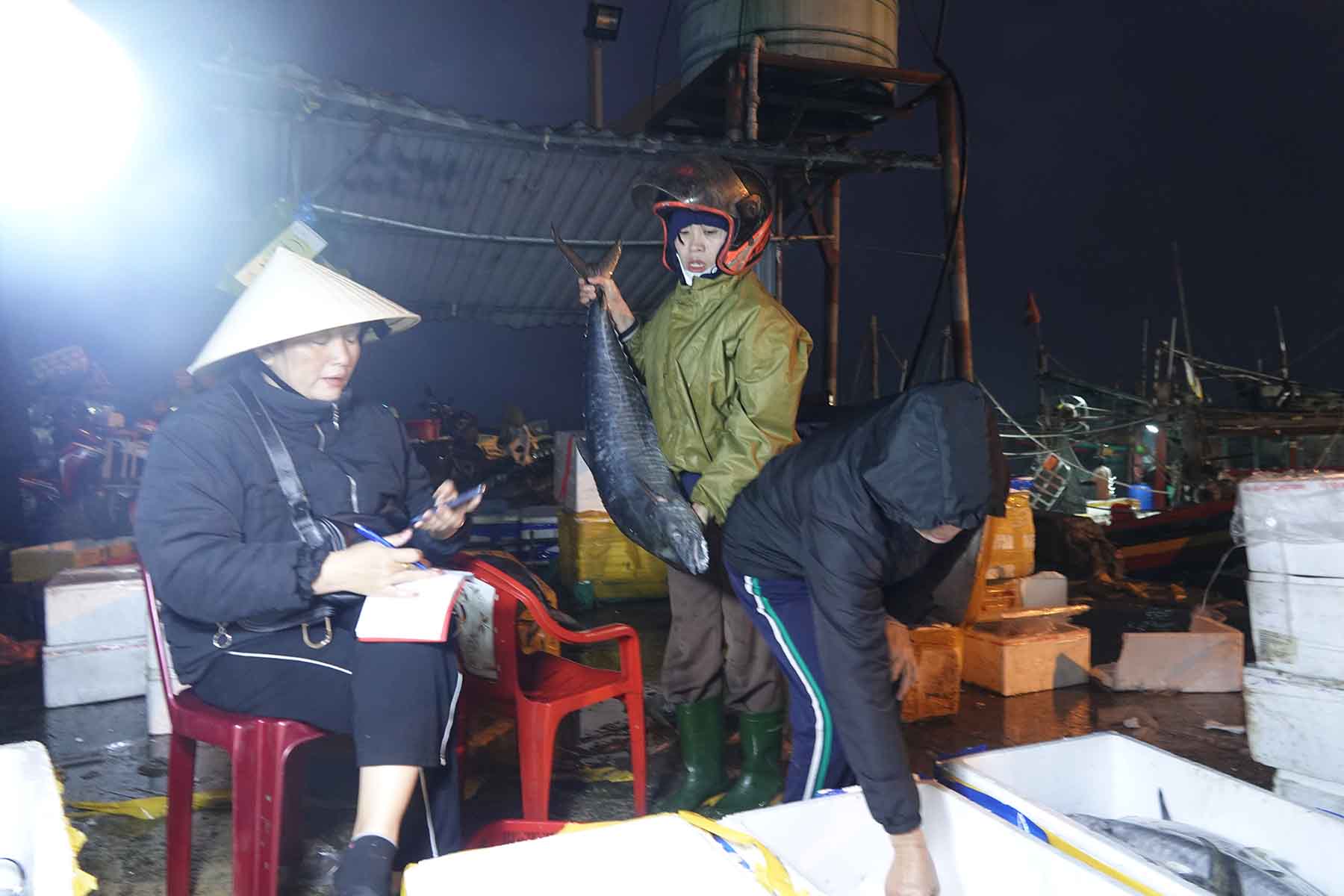 Nu tieu thuong (doi mu bao hiem) dang mua lai ca cua thuong lai de dua len cho huyen ban. Anh: Tran Tuan.