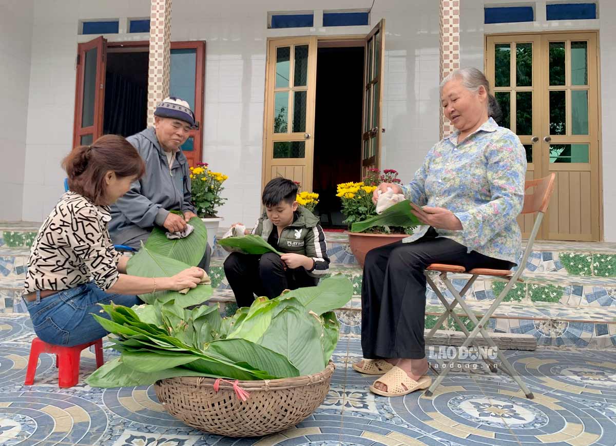 Ms. Thu, her elderly parents and son prepare dong leaves to wrap banh chung. Photo: Luong Ha
