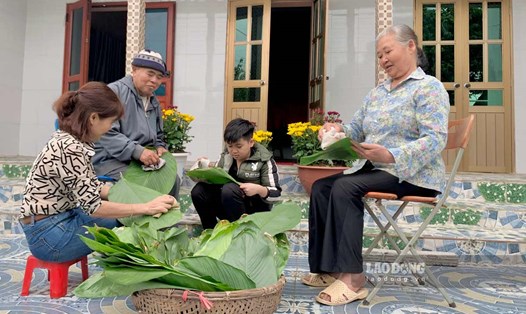Chị Thu cùng bố mẹ già và con trai chuẩn bị lá dong gói bánh chưng. Ảnh: Lương Hà
