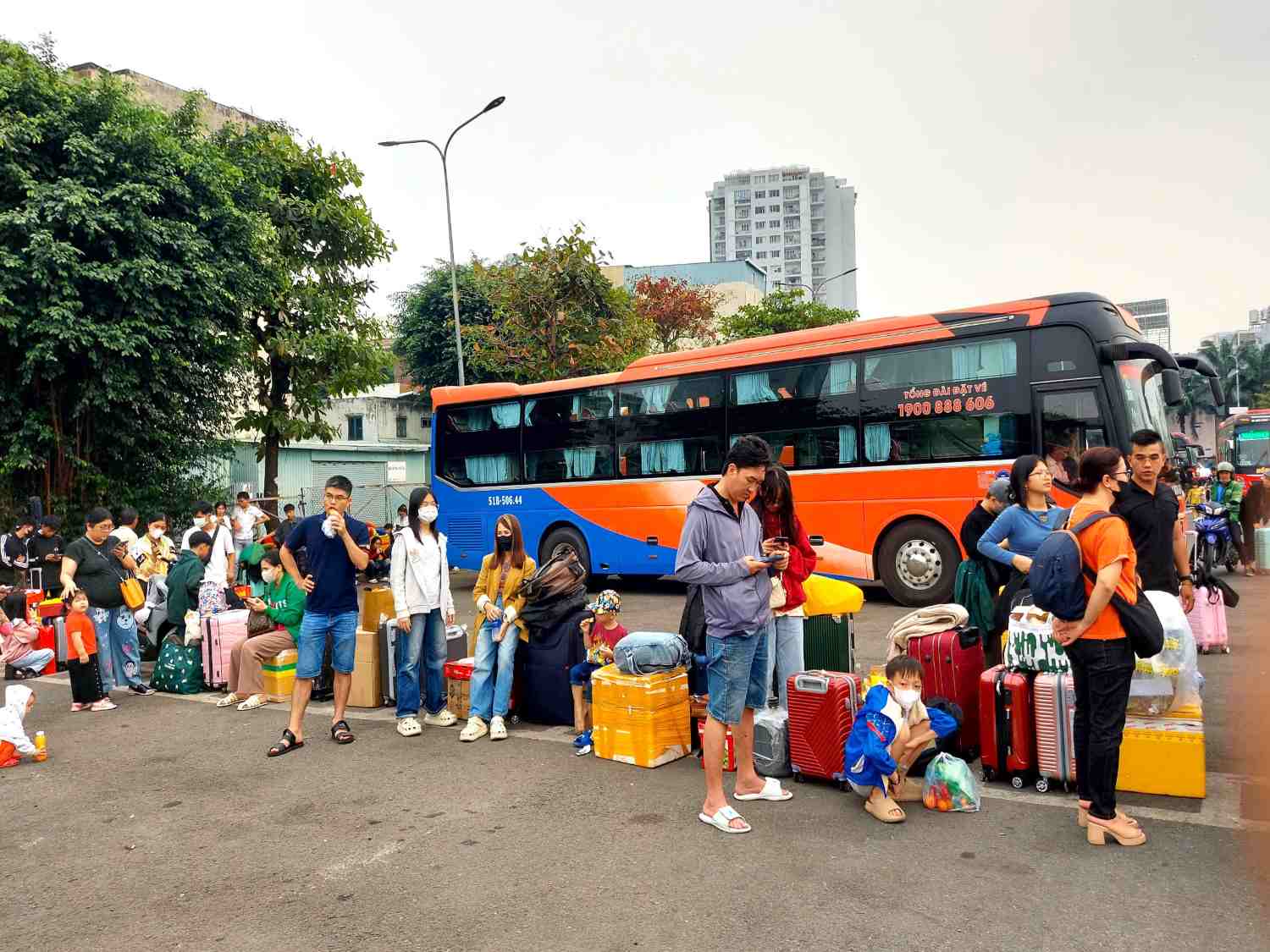 Bên trong bãi đậu xe, hành khách đứng, ngồi, tay xách nách mang, háo hức chờ chuyến xe đưa họ về quê sum họp đón Tết.  Ảnh: Minh Quân