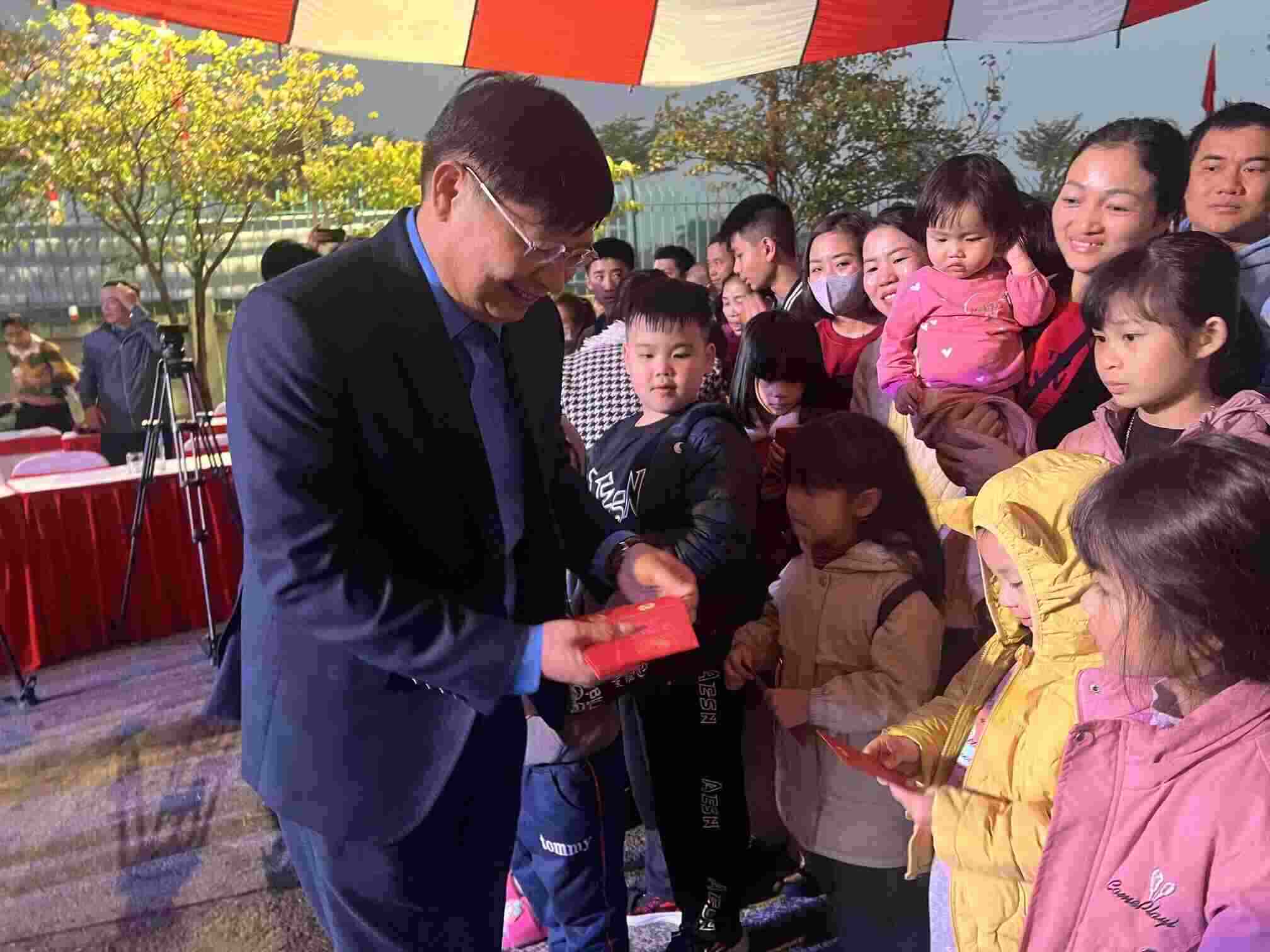 Vice President of the Vietnam General Confederation of Labor Phan Van Anh gives lucky money to workers' children before boarding a free bus to return home to celebrate Tet. Photo: Kieu Vu
