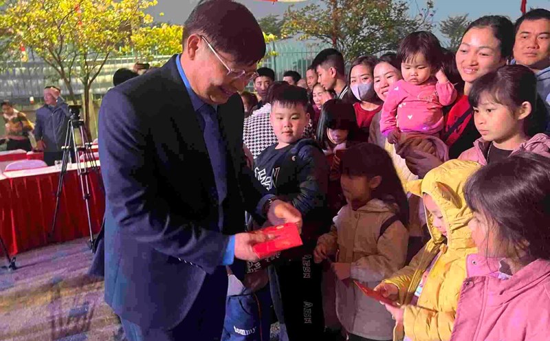 Vice President of the Vietnam General Confederation of Labor Phan Van Anh gives lucky money to workers' children before boarding a free bus to return home to celebrate Tet. Photo: Kieu Vu