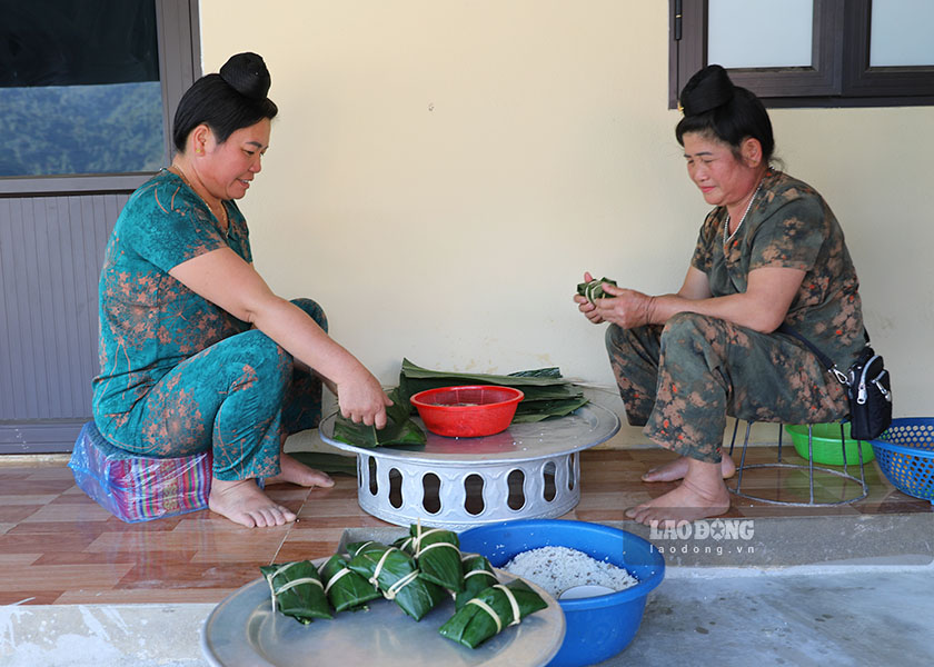 Ba Luong Thi Hieng (ben phai) goi banh chung trong ngoi nha tai dinh cu.