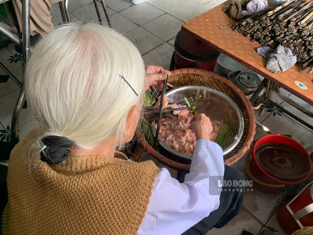 Cu Chin (94 tuoi) phu con chau kep thit vao que tre de nuong. Anh: Ha Vi