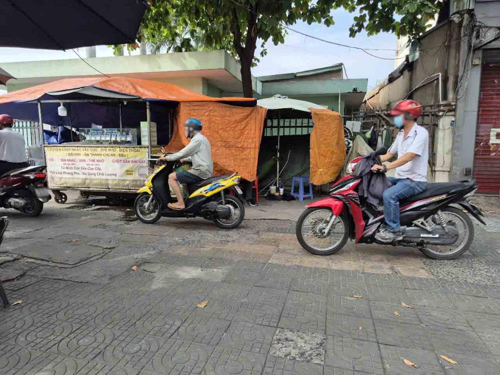 Nguoi dan noi duoi nhau dieu khien xe di tren via he. Anh: Nhu Quynh