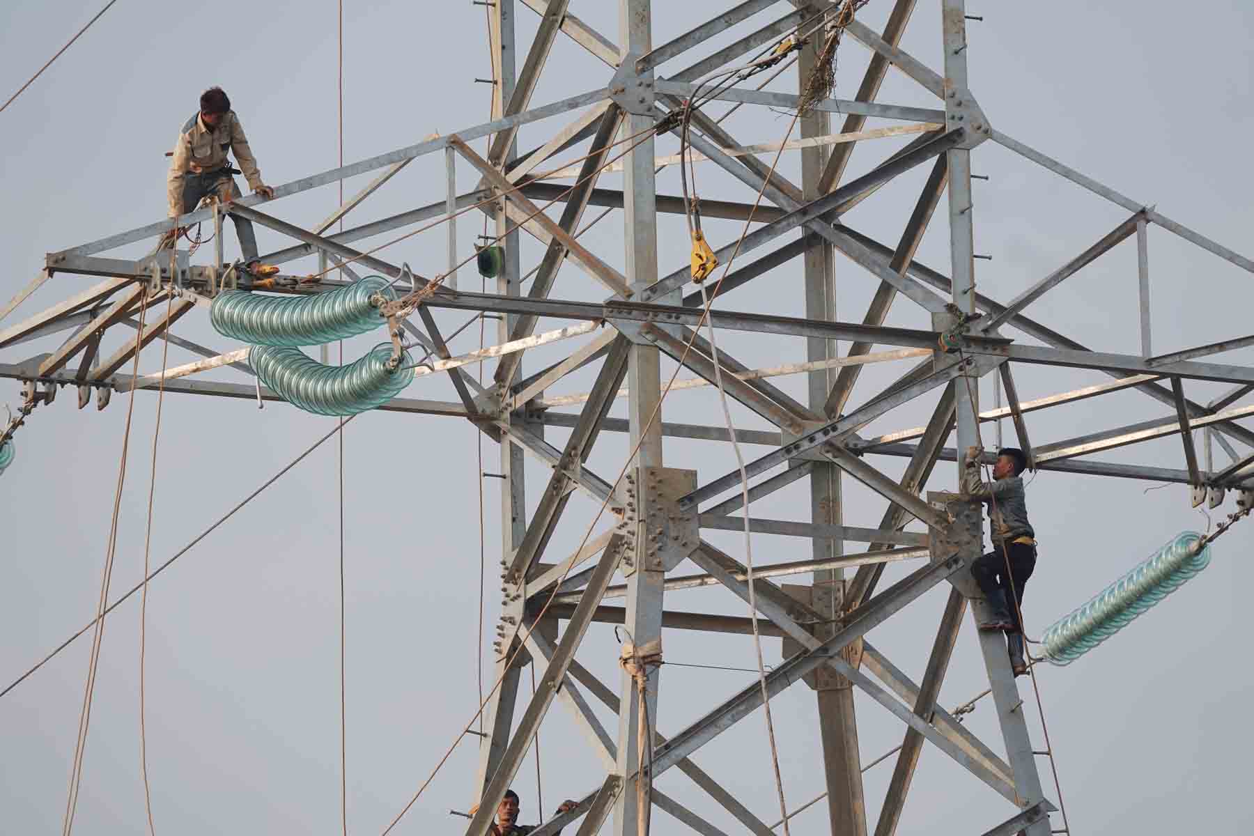 Workers are pulling wires up to electric poles to complete the power grid clearance on the North-South Expressway, through Tan Lam Huong commune. Photo: Tran Tuan.