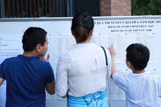Parents and students view the results of the 6th grade entrance exam at a secondary school in Cau Giay district (Hanoi). Photo: Hai Nguyen