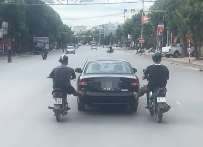 Bac Ninh의 젊은이 2명이 오토바이를 타고 자동차를 밀고 있습니다. 사진: Bac Ninh 공안 교통 경찰서