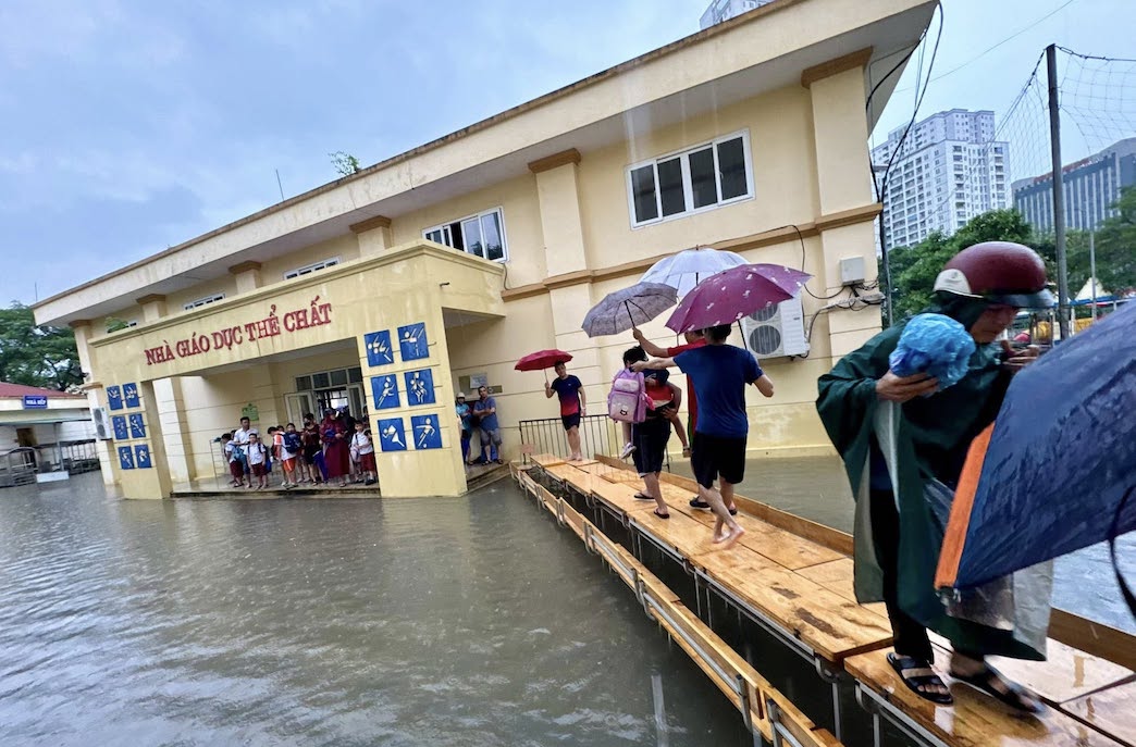 Truoc tinh huong mua lon, ngap lut bat thuong hom 30.9, tap the giao vien Truong Tieu hoc Nam Trung Yen (phuong Yen Hoa, Ha Noi) da ke ban thanh cau, che o de dua cac em hoc sinh ra tan noi cho phu huynh don mot cach an toan. Anh: Nha truong cung cap 