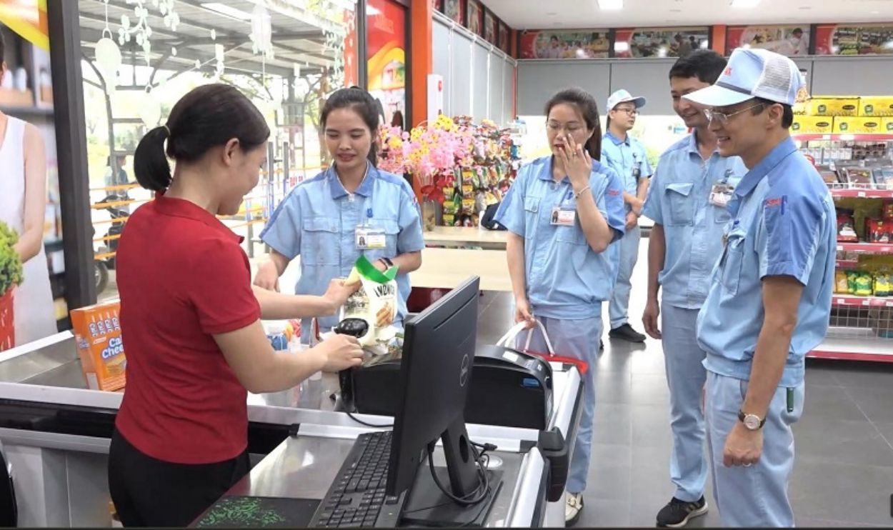 Chu tich Cong doan Cong ty TNHH Dien Stanley Viet Nam Ngo Ngoc Vinh (ngoai cung ben phai) va cong nhan mua hang tai Sieu thi Cong doan cua cong ty. Anh: Ngoc Anh