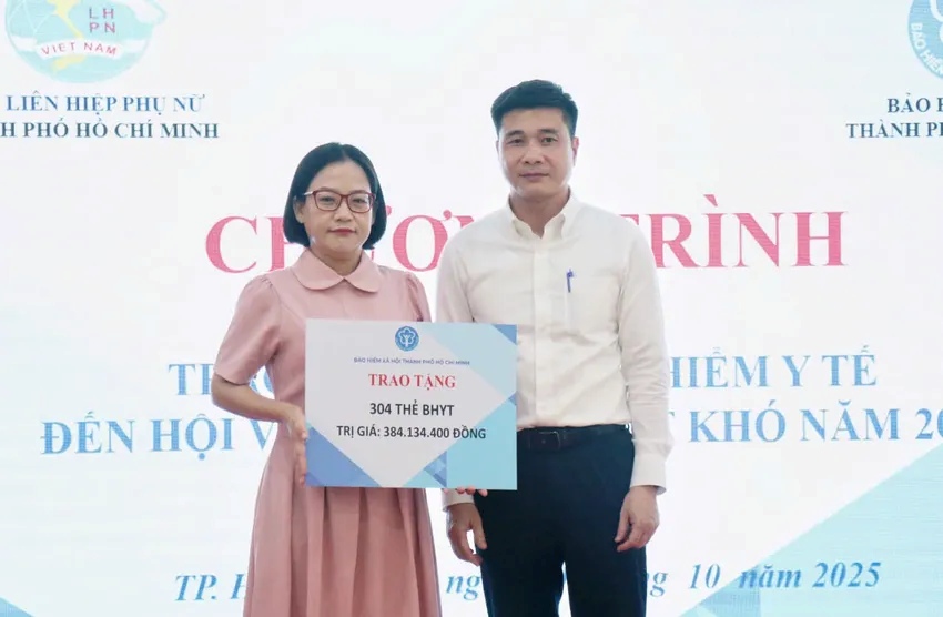 Ong Tran Dung Ha - PGD BHXH TPHCM trao bang tuong trung tang 304 the BHYT cho ba Nguyen Thanh Loan - Pho Chu tich Hoi LHPN TPHCM. Anh: Duc Long