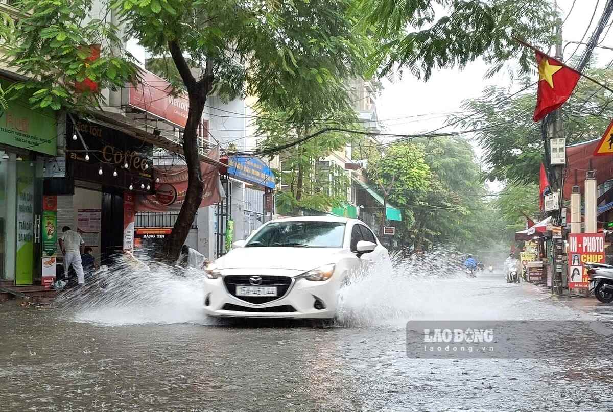 Nuoc ngap ngang banh xe o to, tran len via he duong Nguyen Binh. Ảnh: Mai Dung