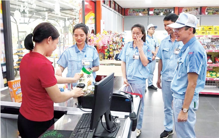 Mr. Ngo Ngoc Vinh - Chairman of the Trade Union of Stanley Vietnam Electricity Company Limited (far right) talks with a worker purchasing goods at the trade union supermarket. Photo: Hanoi City Labor Federation