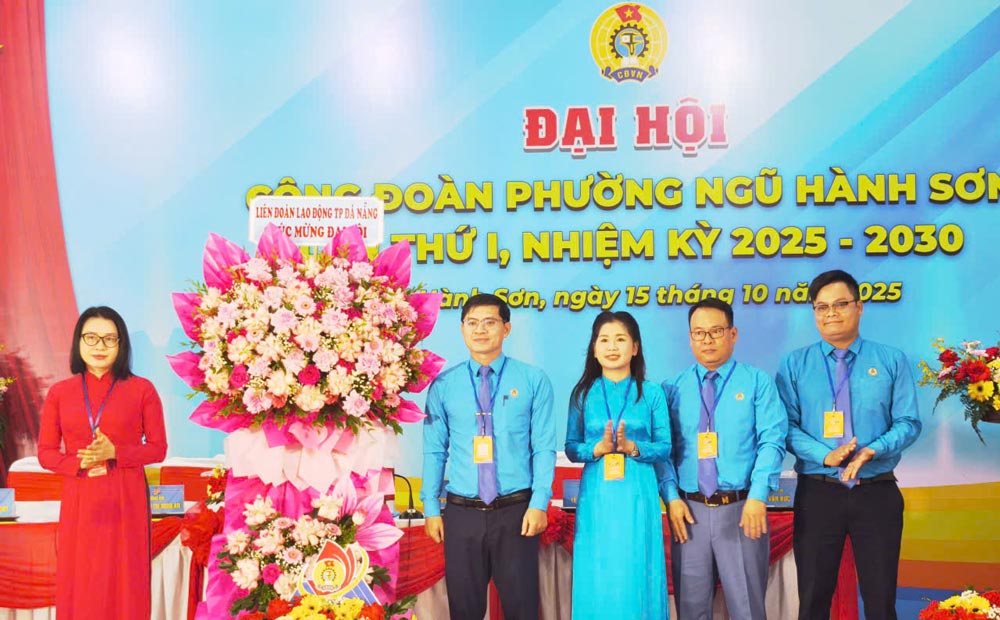 Mme Phan Thi Thuy Linh presidente de la Federation du travail de la ville de Da Nang (a gauche) offre des fleurs pour feliciter le 1er Congres du syndicat du quartier de Ngu Hanh Son mandat 2025-2030. Photo : Tuong Minh
