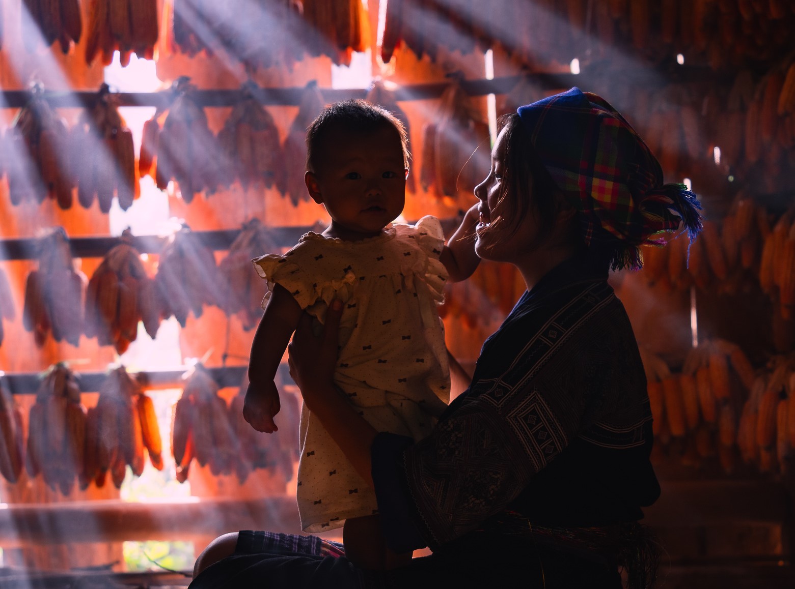 Nhà phơi ngô dưới góc nhìn nhiếp ảnh của anh Vũ Khoa bỗng trở thành không gian đặc biệt, một phông nền ấn tượng để chớp lấy khoảnh khắc vừa giản dị vừa đặc sắc của mẹ con người H'Mông.