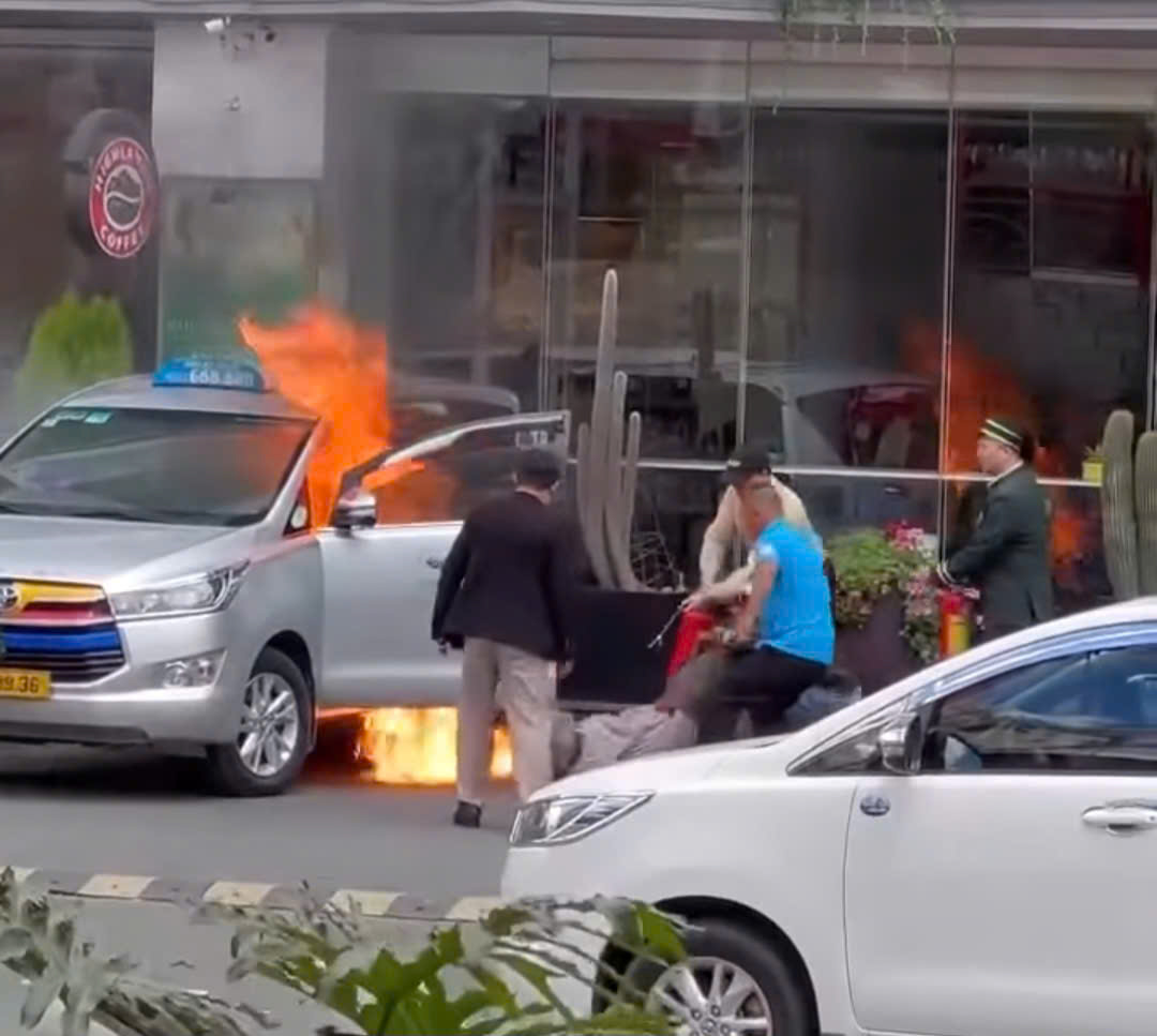 Nhan vien khach san va nguoi dan tap trung dap lua cuu tai xe mac ket trong taxi. Anh: Cat tu clip