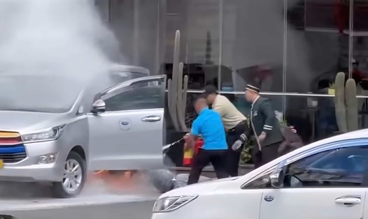 Nhân viên khách sạn và người dân ở Đà Lạt (Lâm Đồng) kịp thời giải cứu tài xế mắc kẹt trong taxi bốc cháy. Ảnh: Cắt từ clip